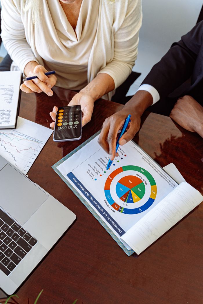 Mastering the First Impression: Your intriguing post title goes here Two business professionals discussing financial documents and strategies at an office desk.