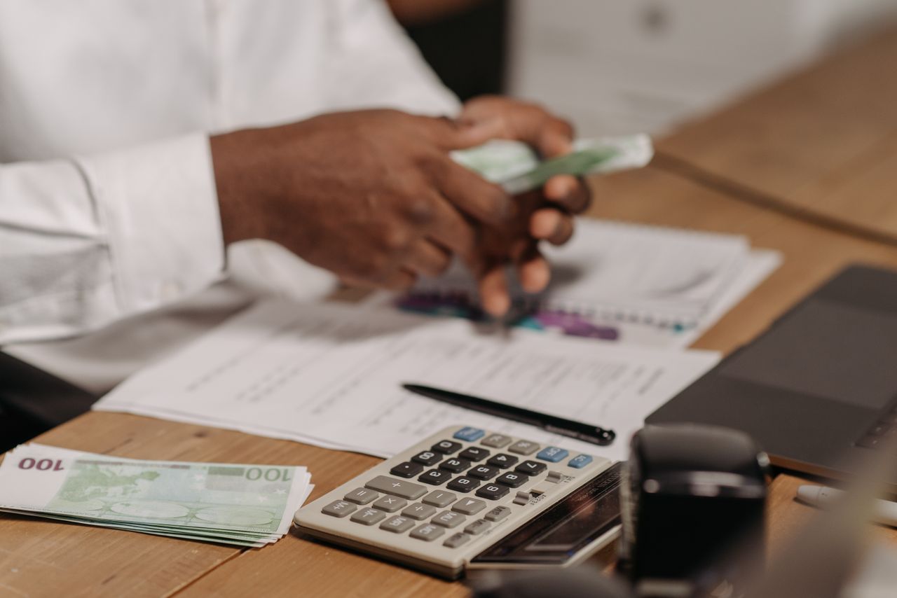 The Art of Drawing Readers In: Your attractive post title goes here Hands counting euro bills on a wooden desk with calculator, financial documents, and laptop nearby.