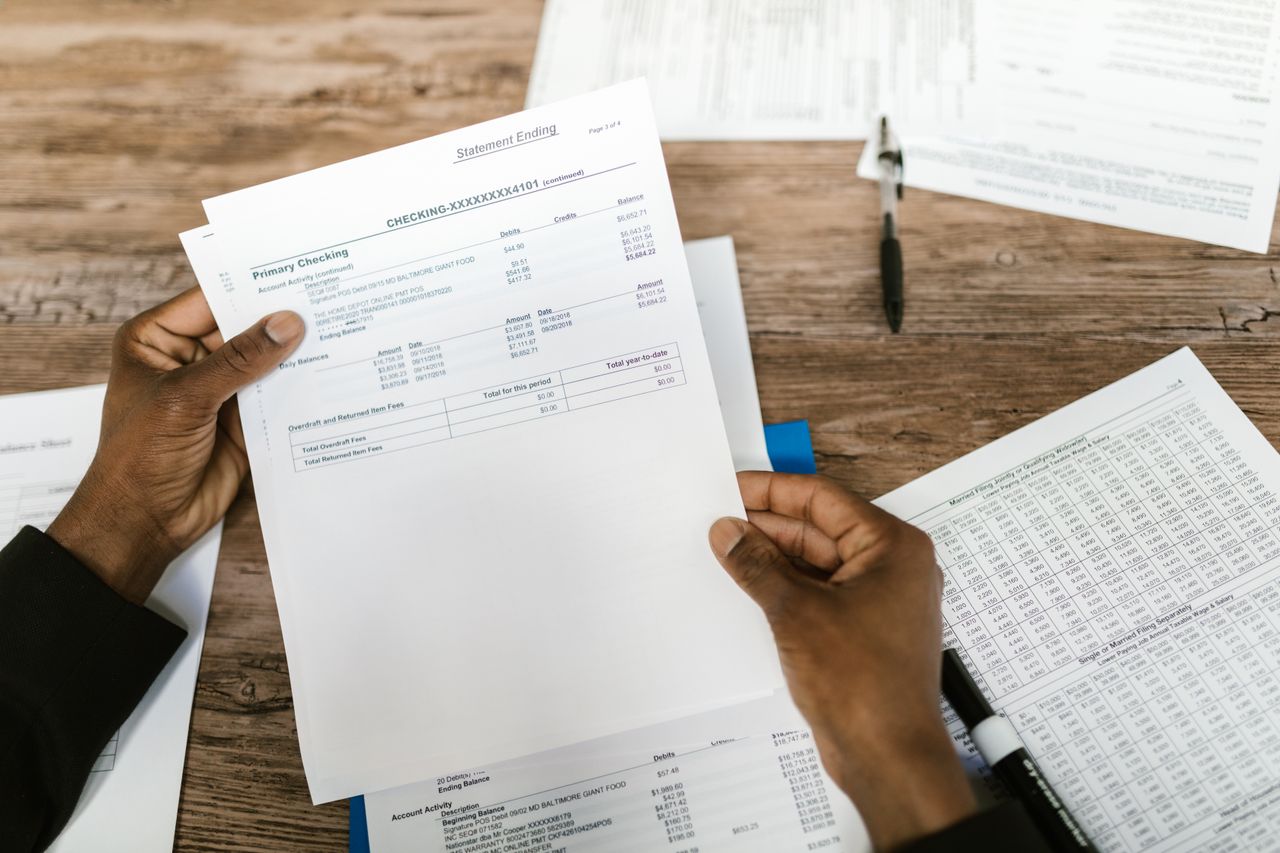 brand-03 Hands holding financial papers for tax preparation and analysis.