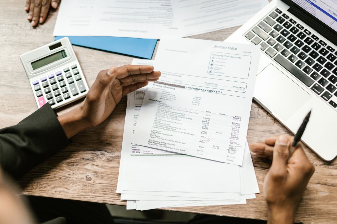 creative-03 Hands holding financial documents with calculator and laptop on office desk, business analysis scene.